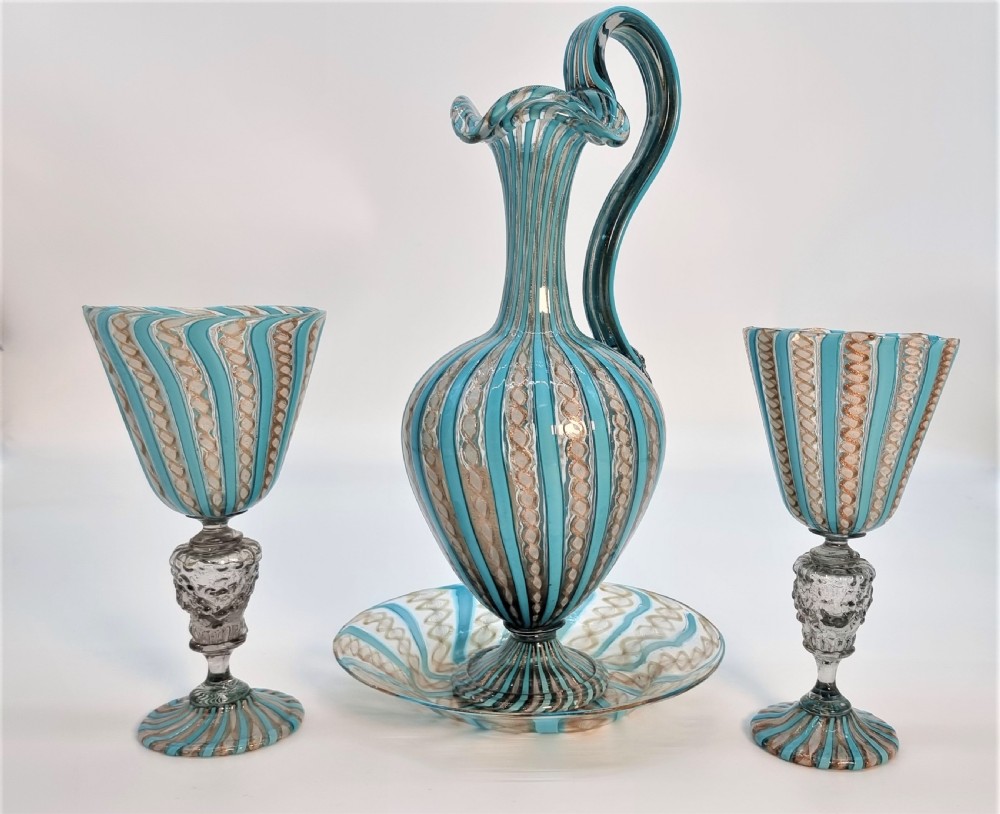 An antique Venetian glass claret set featuring a striped turquoise blue and white latticinio ewer with handle, matching saucer, and two stemware goblets. View II