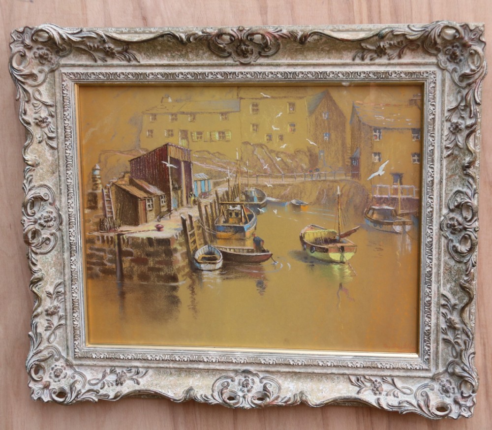 A framed pastel drawing depicting Polperro Harbour with fishing boats and stone cottages, set within an ornate swept frame.