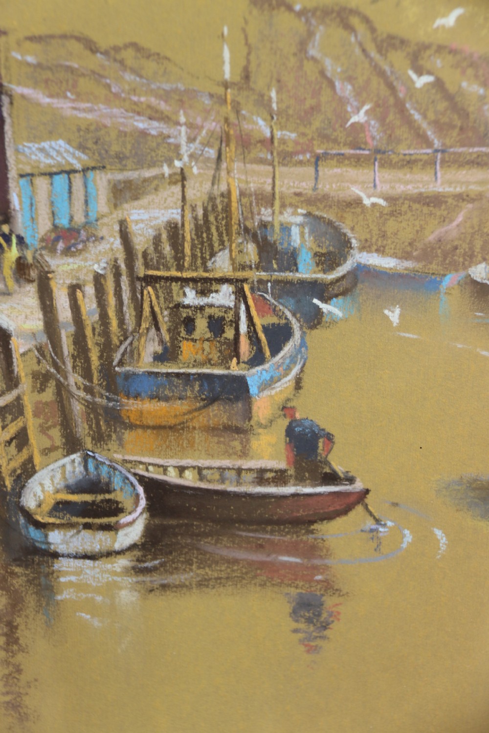 A framed pastel drawing depicting Polperro Harbour with fishing boats and stone cottages, set within an ornate swept frame. View III
