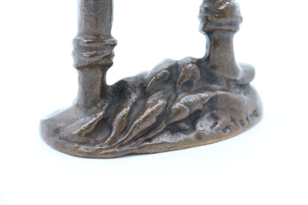 A dark brown patinated bronze statuette depicting a figure in historic costume playing a pipe while standing on a textured base. View X