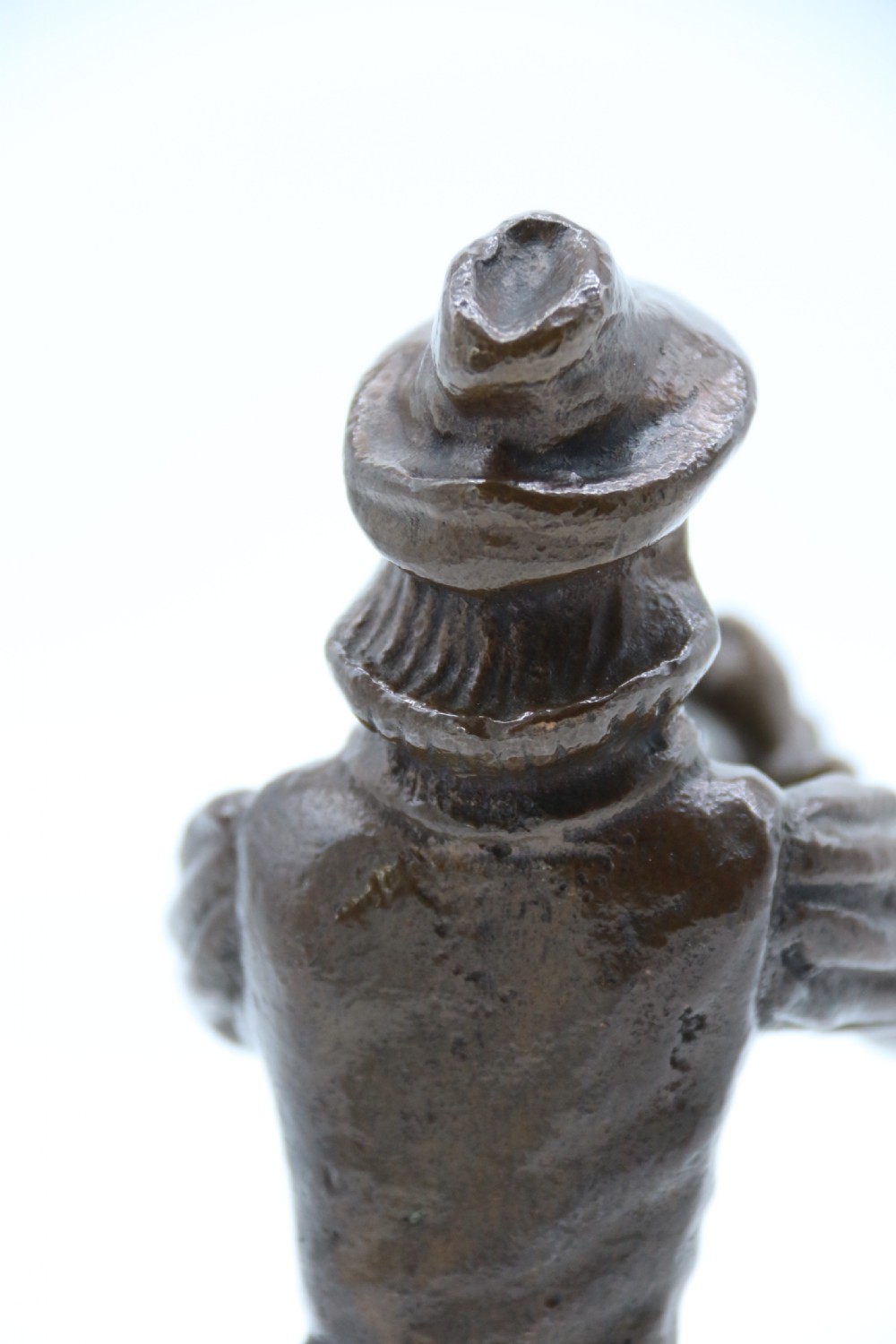 A dark brown patinated bronze statuette depicting a figure in historic costume playing a pipe while standing on a textured base. View XIII