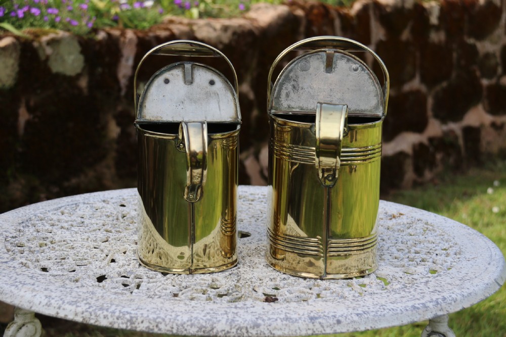 A pair of polished 19th-century brass watering cans in differing sizes featuring reeded cylindrical bodies, arched top handles, and angled spouts. View VI