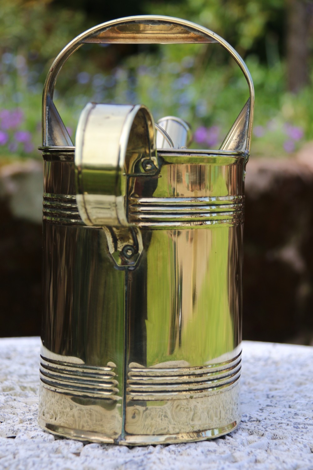 A pair of polished 19th-century brass watering cans in differing sizes featuring reeded cylindrical bodies, arched top handles, and angled spouts. View XII