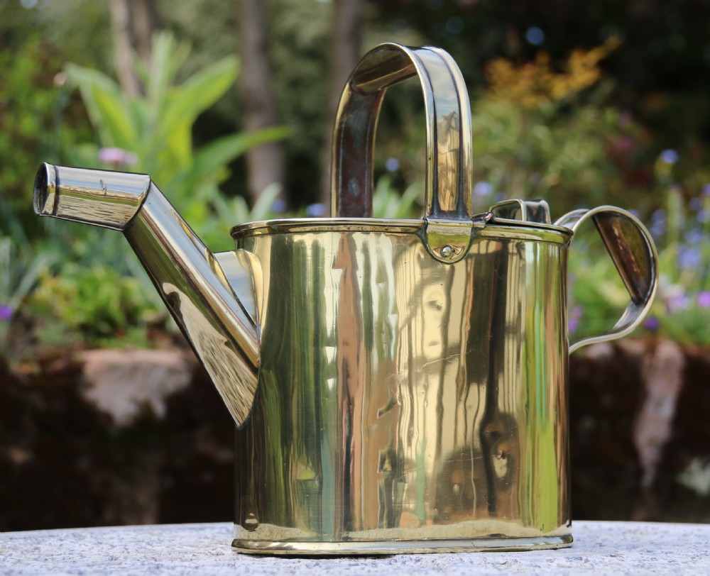 A pair of polished 19th-century brass watering cans in differing sizes featuring reeded cylindrical bodies, arched top handles, and angled spouts. View XVII