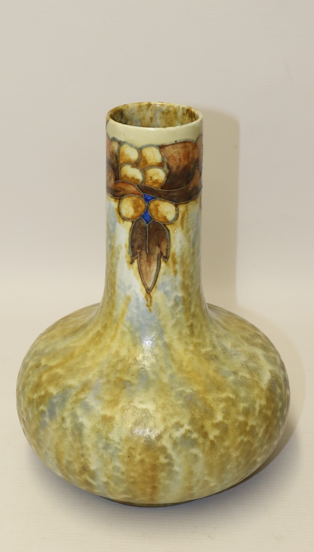 An English Cranston art pottery vase with a bulbous base, cylindrical neck, and a mottled yellow and brown glaze featuring a stylised floral motif.
