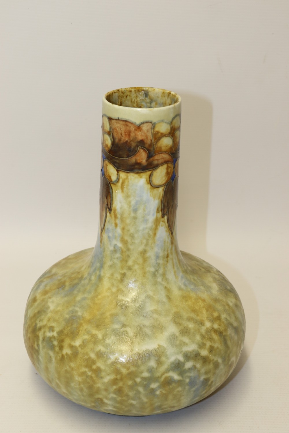 An English Cranston art pottery vase with a bulbous base, cylindrical neck, and a mottled yellow and brown glaze featuring a stylised floral motif. View III