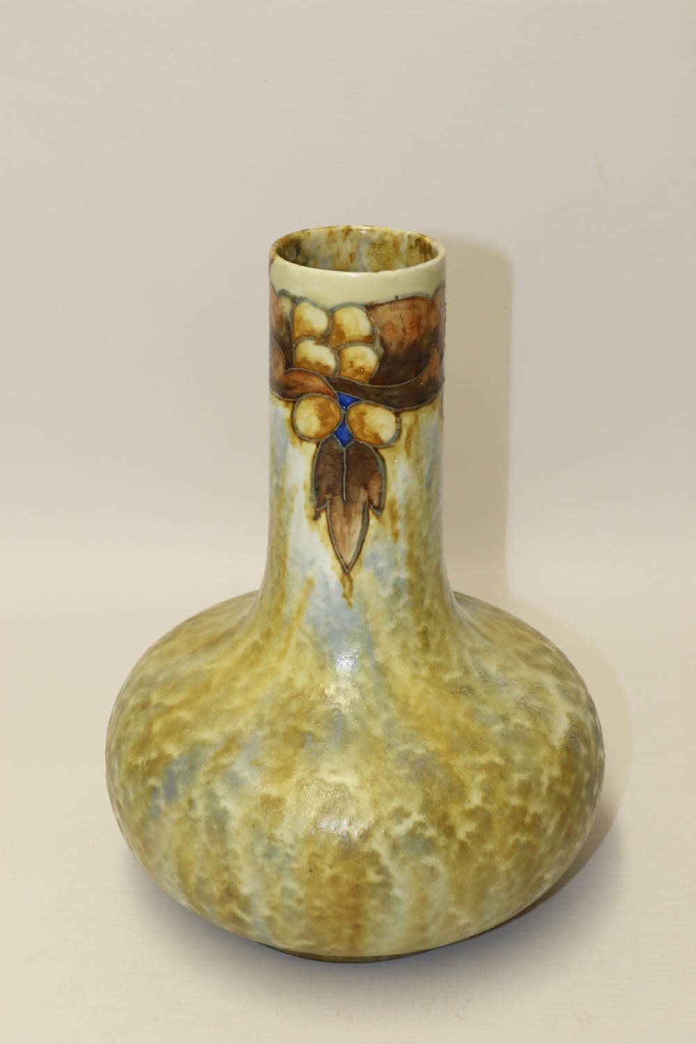 An English Cranston art pottery vase with a bulbous base, cylindrical neck, and a mottled yellow and brown glaze featuring a stylised floral motif. View V