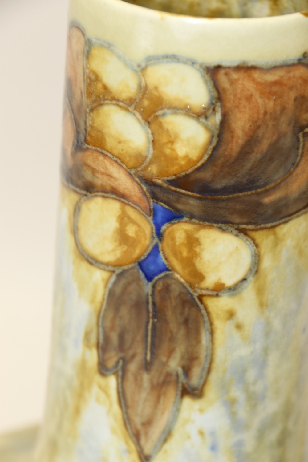 An English Cranston art pottery vase with a bulbous base, cylindrical neck, and a mottled yellow and brown glaze featuring a stylised floral motif. View VII