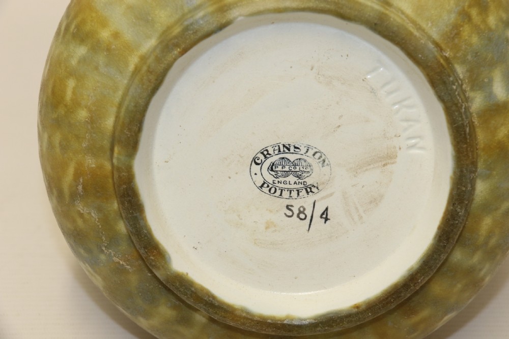 An English Cranston art pottery vase with a bulbous base, cylindrical neck, and a mottled yellow and brown glaze featuring a stylised floral motif. View VIII