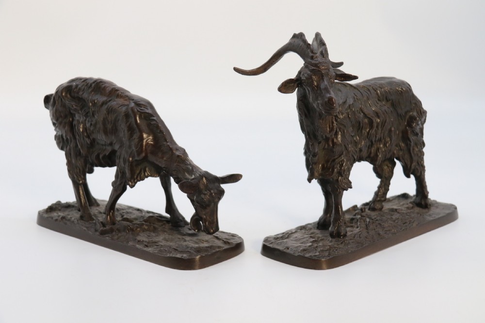 A pair of 19th-century French dark brown patinated bronze sculptures depicting a standing horned goat and a grazing goat on naturalistic bases. View II