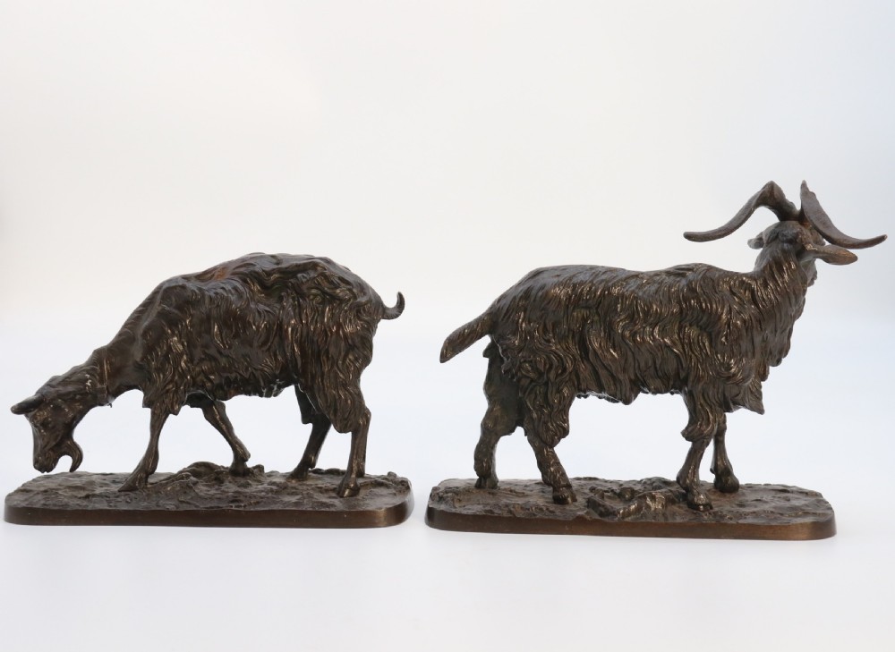 A pair of 19th-century French dark brown patinated bronze sculptures depicting a standing horned goat and a grazing goat on naturalistic bases. View V