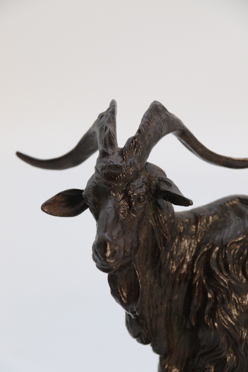 A pair of 19th-century French dark brown patinated bronze sculptures depicting a standing horned goat and a grazing goat on naturalistic bases. View XXX