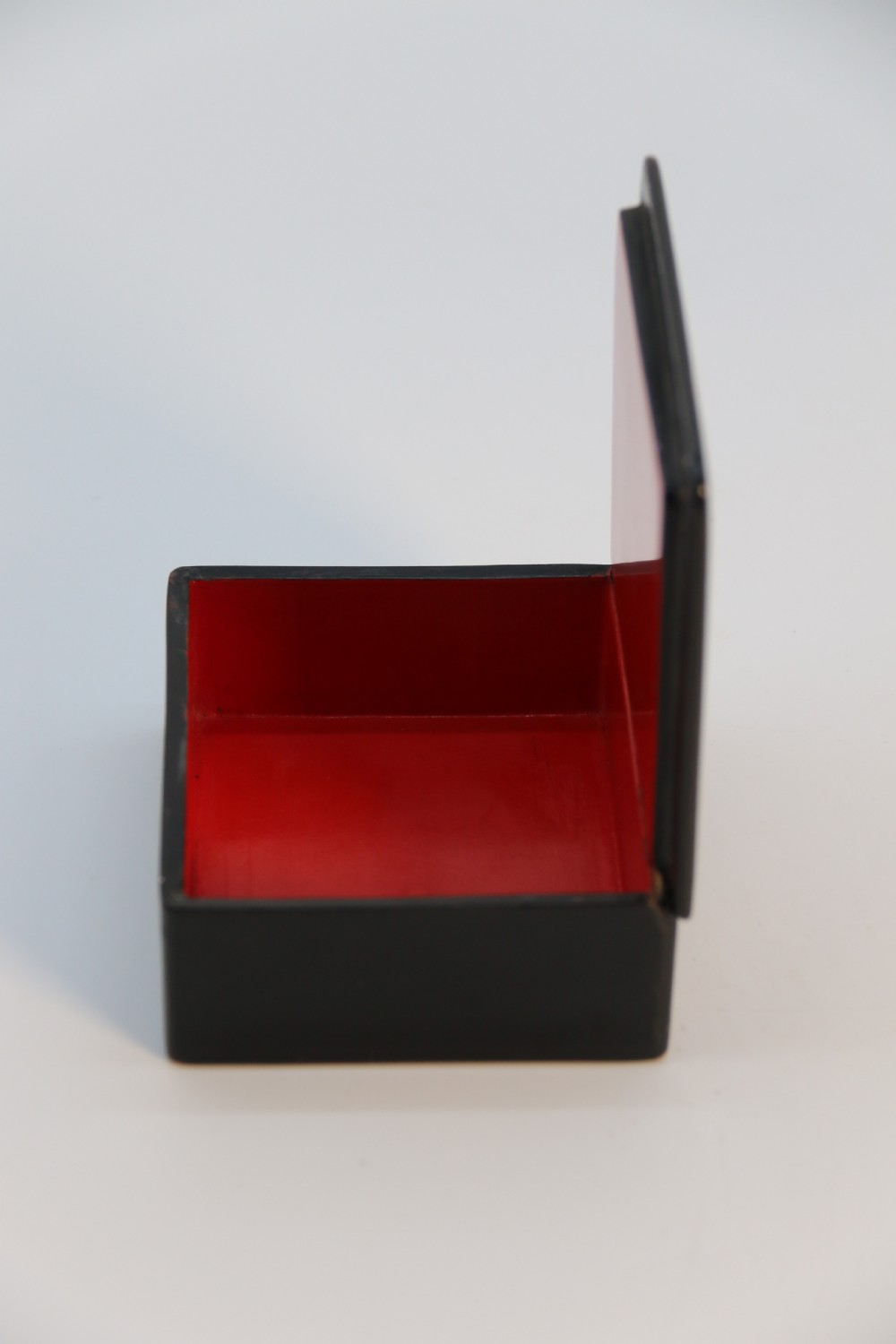 A square black lacquered box featuring a hand-painted portrait of a young woman with brown hair and a red ribbon. View IX