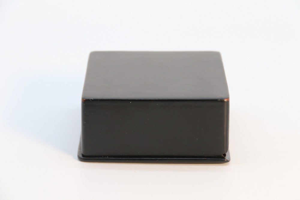 A square black lacquered box featuring a hand-painted portrait of a young woman with brown hair and a red ribbon. View X