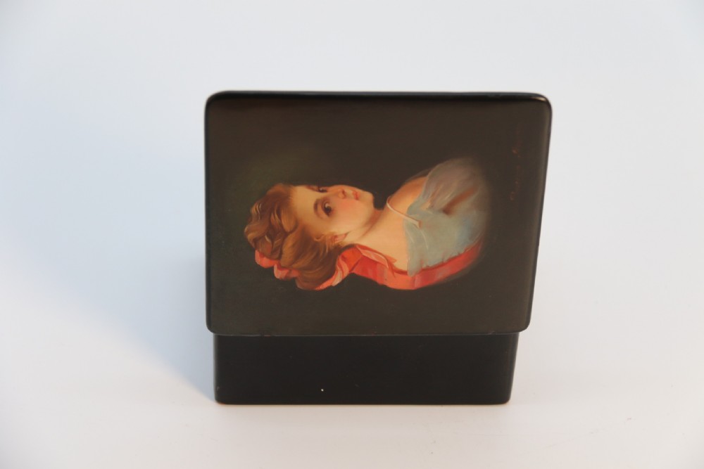 A square black lacquered box featuring a hand-painted portrait of a young woman with brown hair and a red ribbon. View XIV