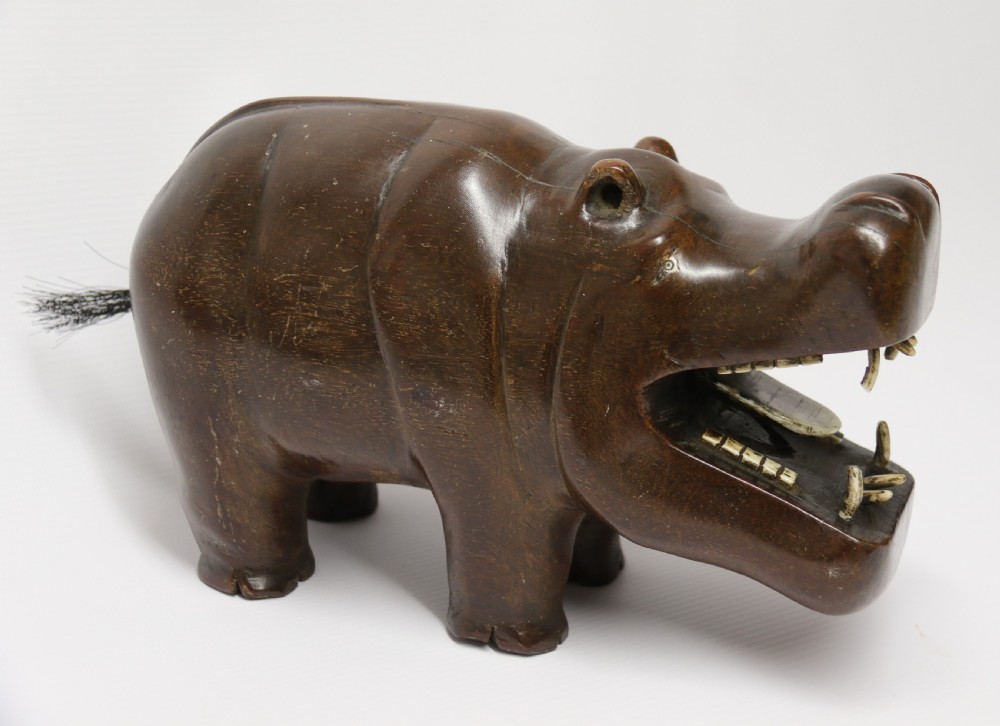 A dark brown carved hardwood hippopotamus sculpture with open mouth detailing inset bone teeth and carved body folds. View II