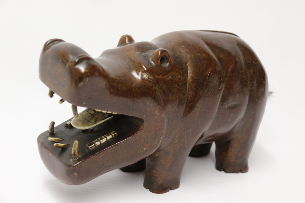A dark brown carved hardwood hippopotamus sculpture with open mouth detailing inset bone teeth and carved body folds. View III