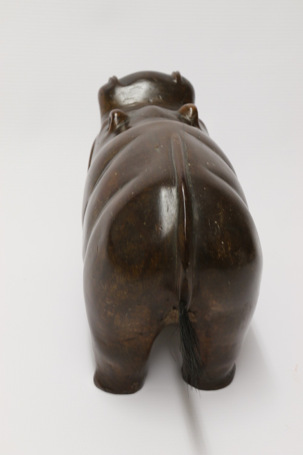 A dark brown carved hardwood hippopotamus sculpture with open mouth detailing inset bone teeth and carved body folds. View IX