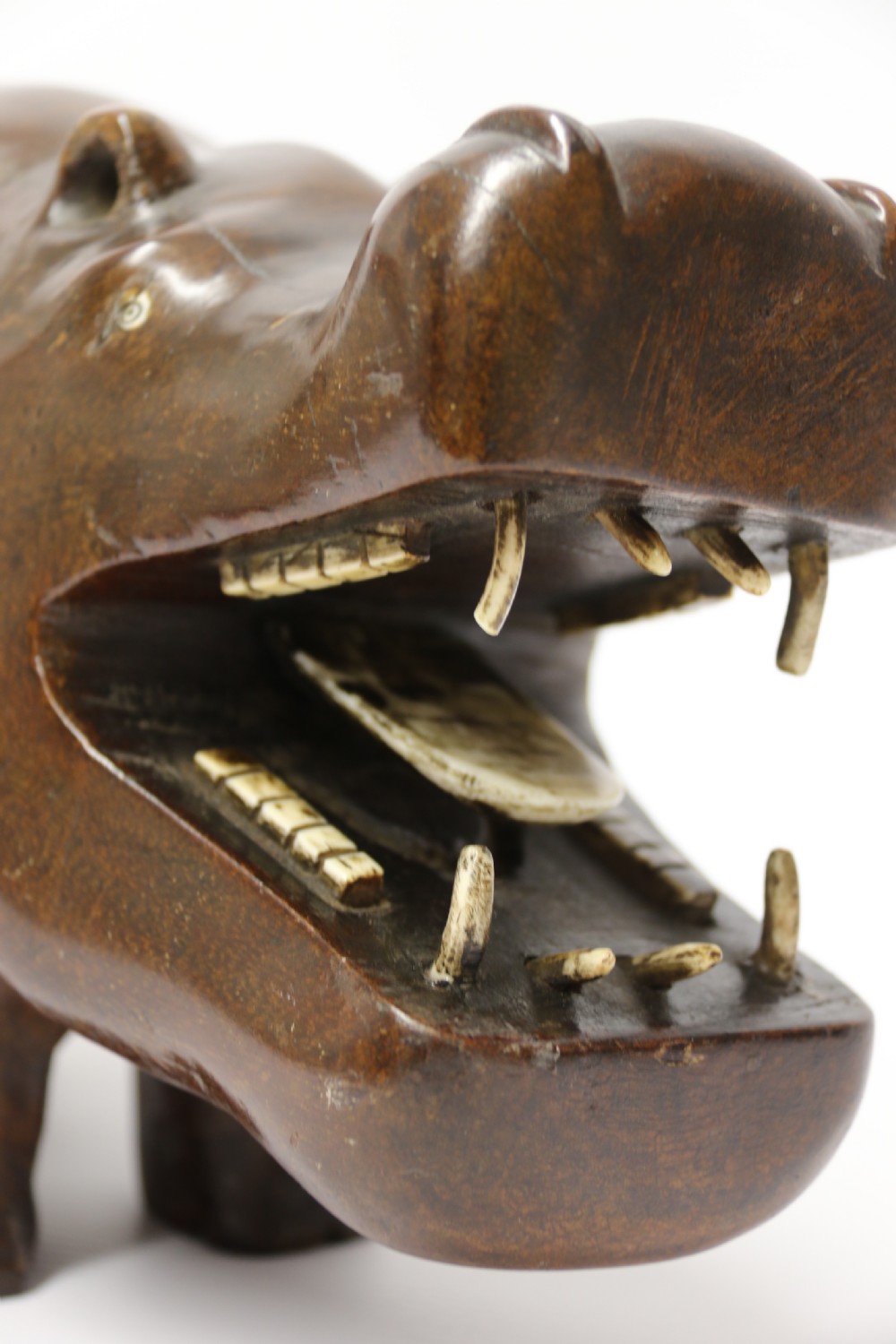 A dark brown carved hardwood hippopotamus sculpture with open mouth detailing inset bone teeth and carved body folds. View XII