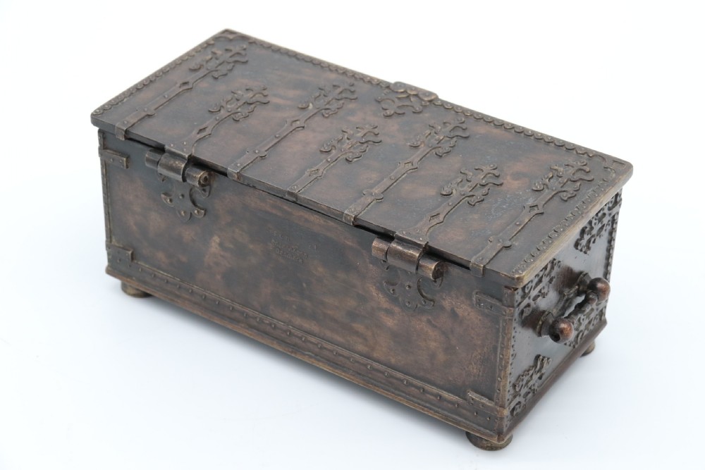 A dark brown patinated cast metal trinket box fashioned in the form of a medieval coffer with relief figures and metal strapwork details. View II