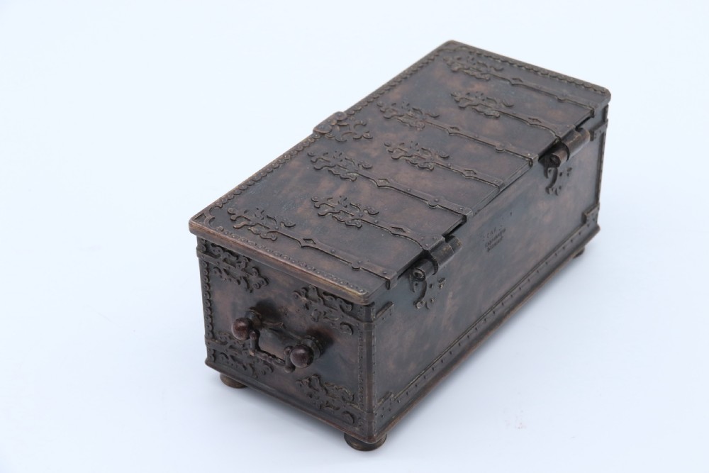 A dark brown patinated cast metal trinket box fashioned in the form of a medieval coffer with relief figures and metal strapwork details. View IV