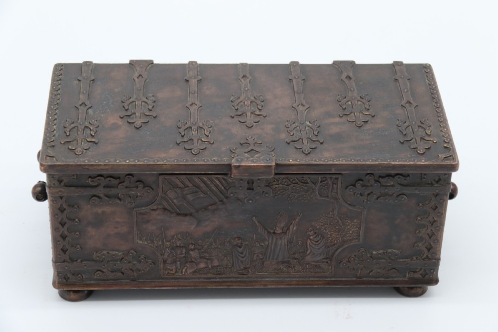 A dark brown patinated cast metal trinket box fashioned in the form of a medieval coffer with relief figures and metal strapwork details. View V