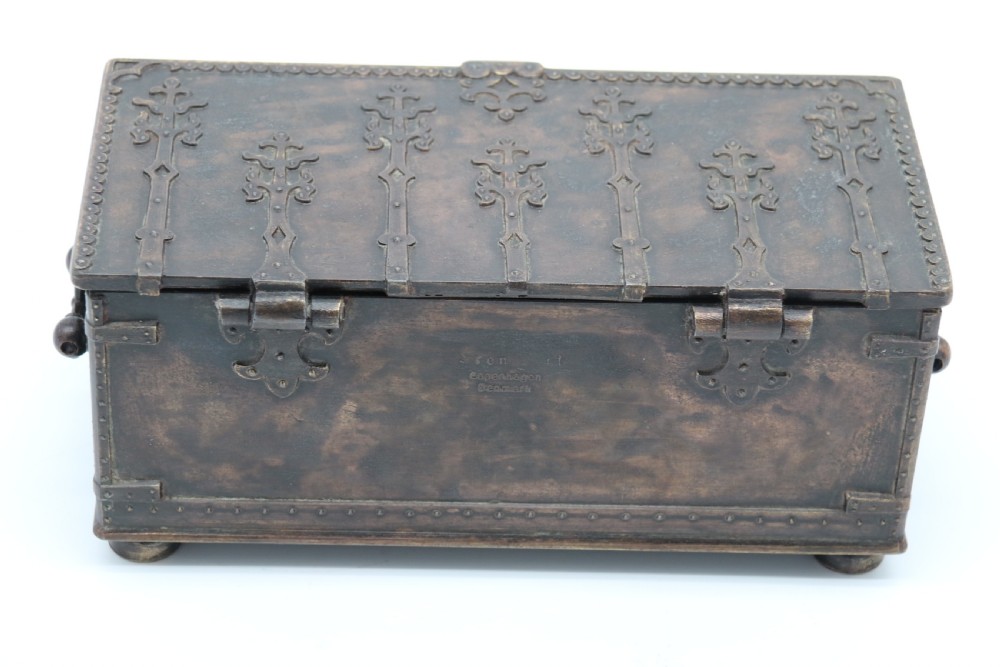 A dark brown patinated cast metal trinket box fashioned in the form of a medieval coffer with relief figures and metal strapwork details. View VI