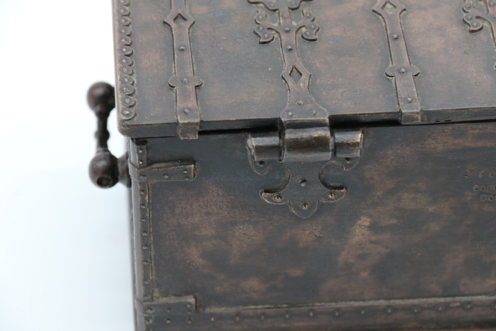 A dark brown patinated cast metal trinket box fashioned in the form of a medieval coffer with relief figures and metal strapwork details. View X