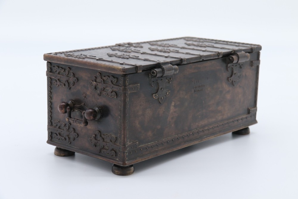 A dark brown patinated cast metal trinket box fashioned in the form of a medieval coffer with relief figures and metal strapwork details. View XX