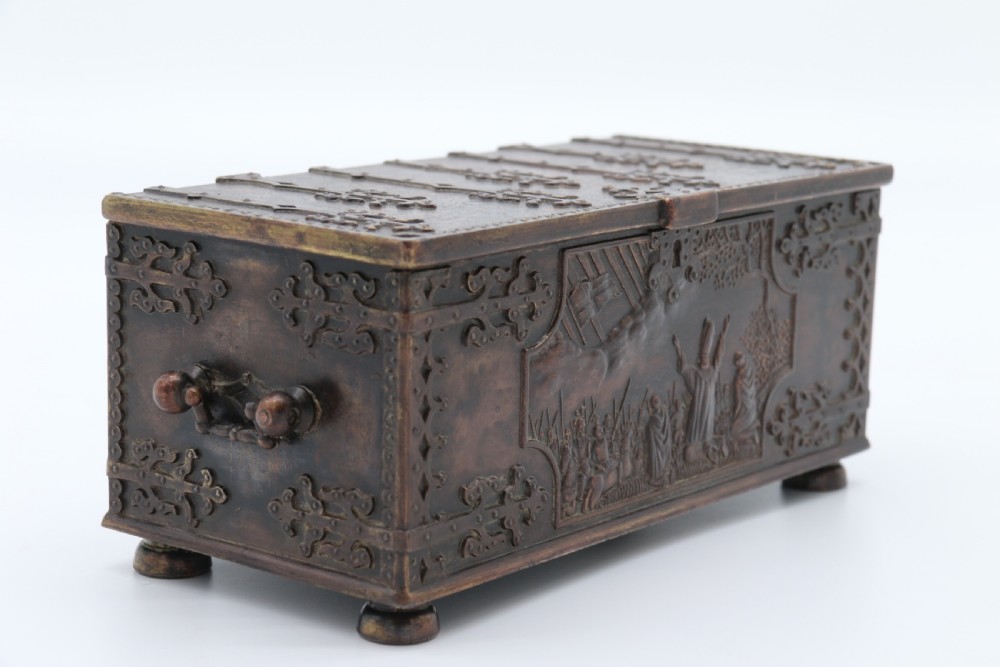 A dark brown patinated cast metal trinket box fashioned in the form of a medieval coffer with relief figures and metal strapwork details. View XXI