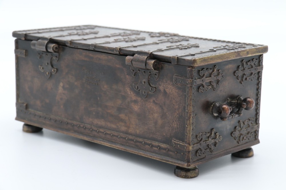 A dark brown patinated cast metal trinket box fashioned in the form of a medieval coffer with relief figures and metal strapwork details. View XXII