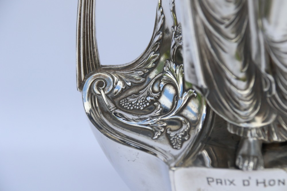 An Art Nouveau silver-plated WMF vase featuring a sculpted maiden figure in relief, sweeping organic handles, and a cut glass rim insert. View VI