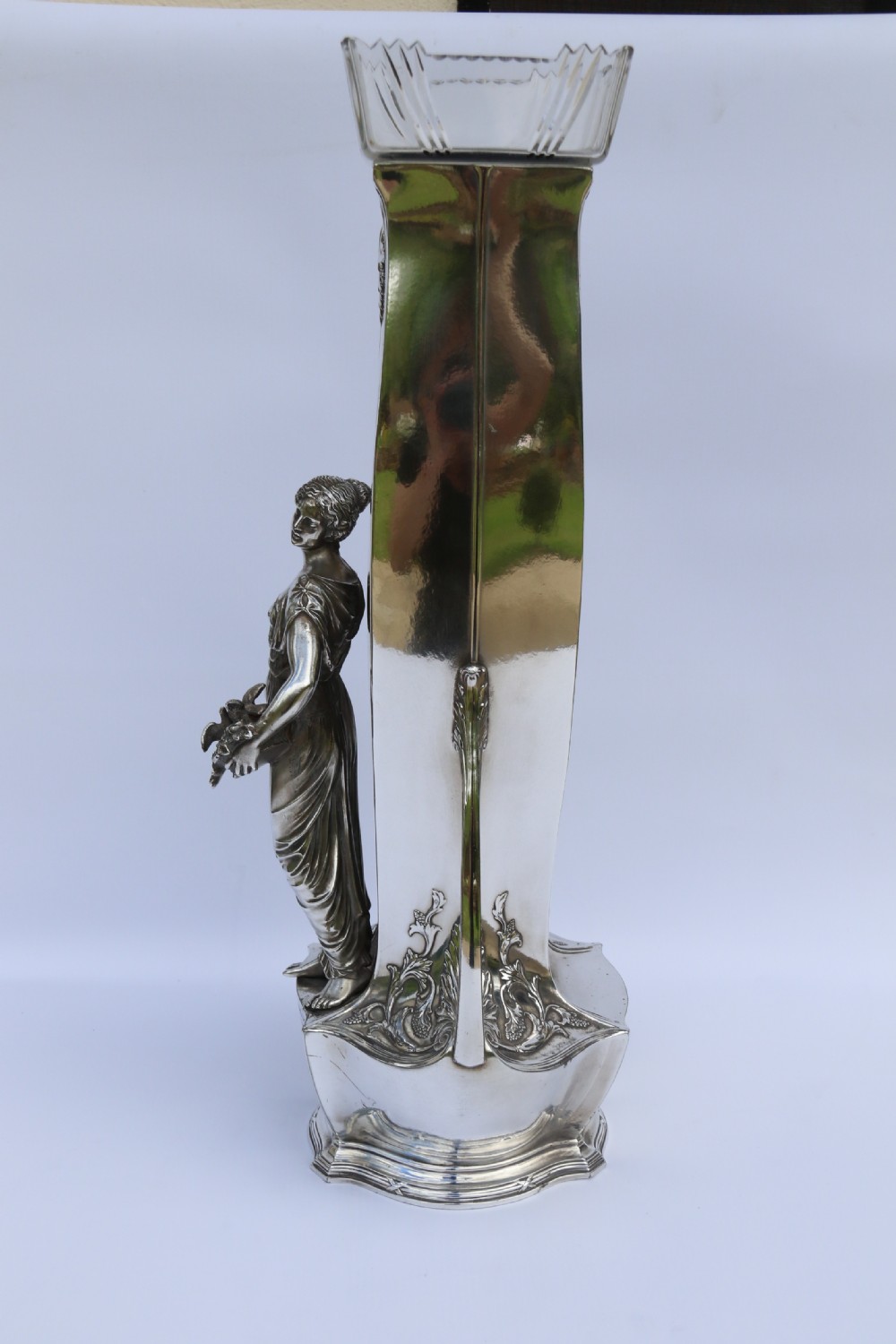 An Art Nouveau silver-plated WMF vase featuring a sculpted maiden figure in relief, sweeping organic handles, and a cut glass rim insert. View X