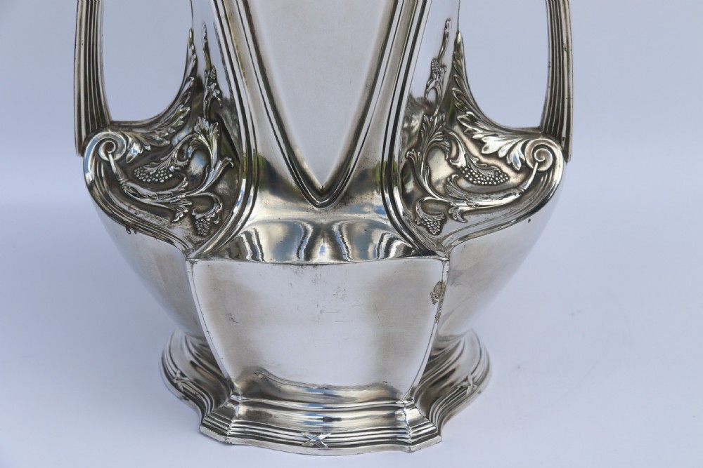 An Art Nouveau silver-plated WMF vase featuring a sculpted maiden figure in relief, sweeping organic handles, and a cut glass rim insert. View XIV