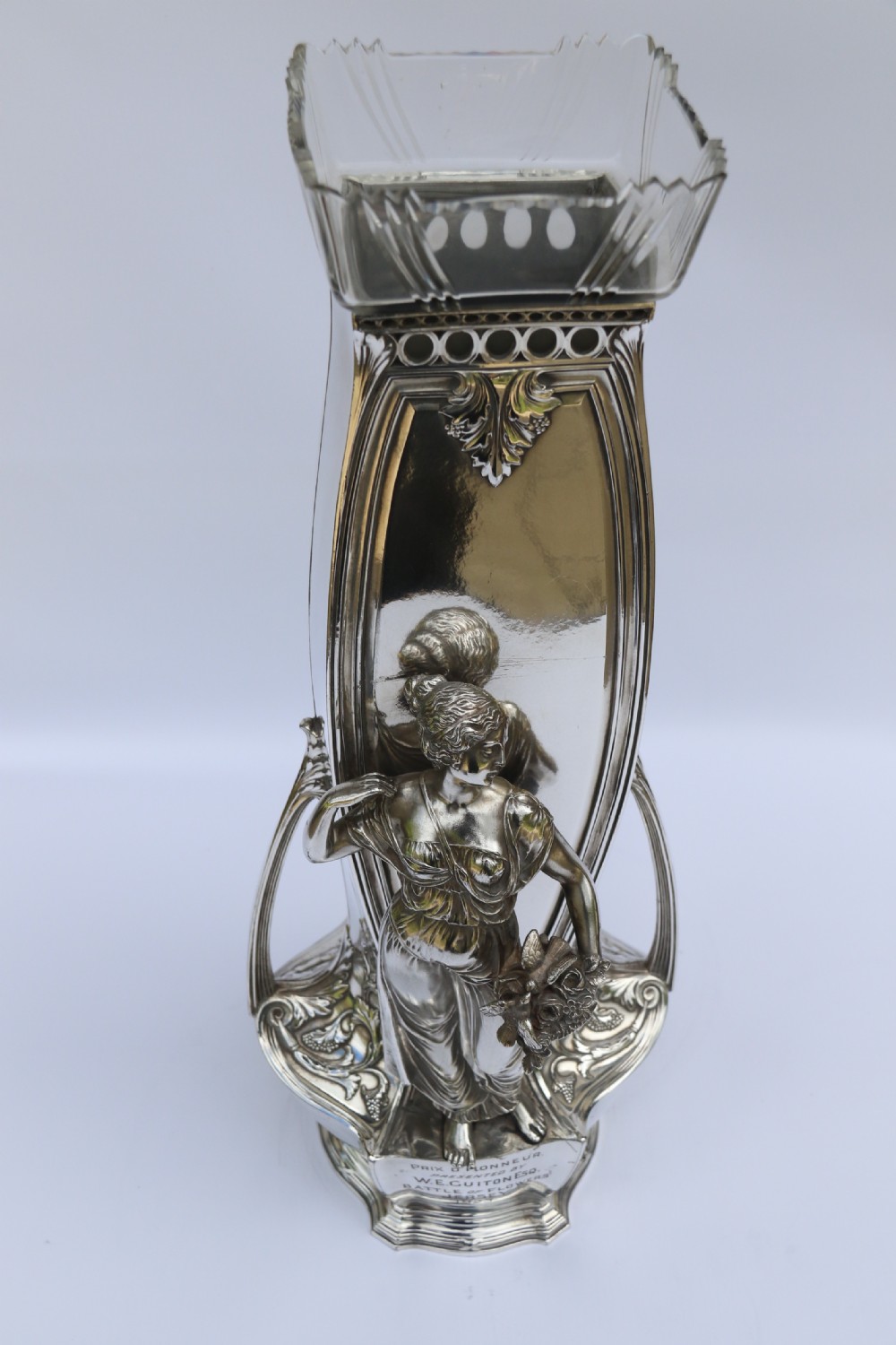 An Art Nouveau silver-plated WMF vase featuring a sculpted maiden figure in relief, sweeping organic handles, and a cut glass rim insert. View XXVI