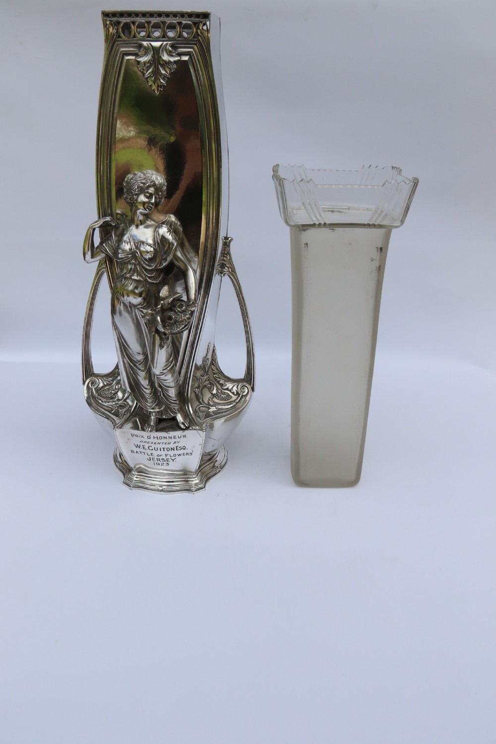 An Art Nouveau silver-plated WMF vase featuring a sculpted maiden figure in relief, sweeping organic handles, and a cut glass rim insert. View XXVII