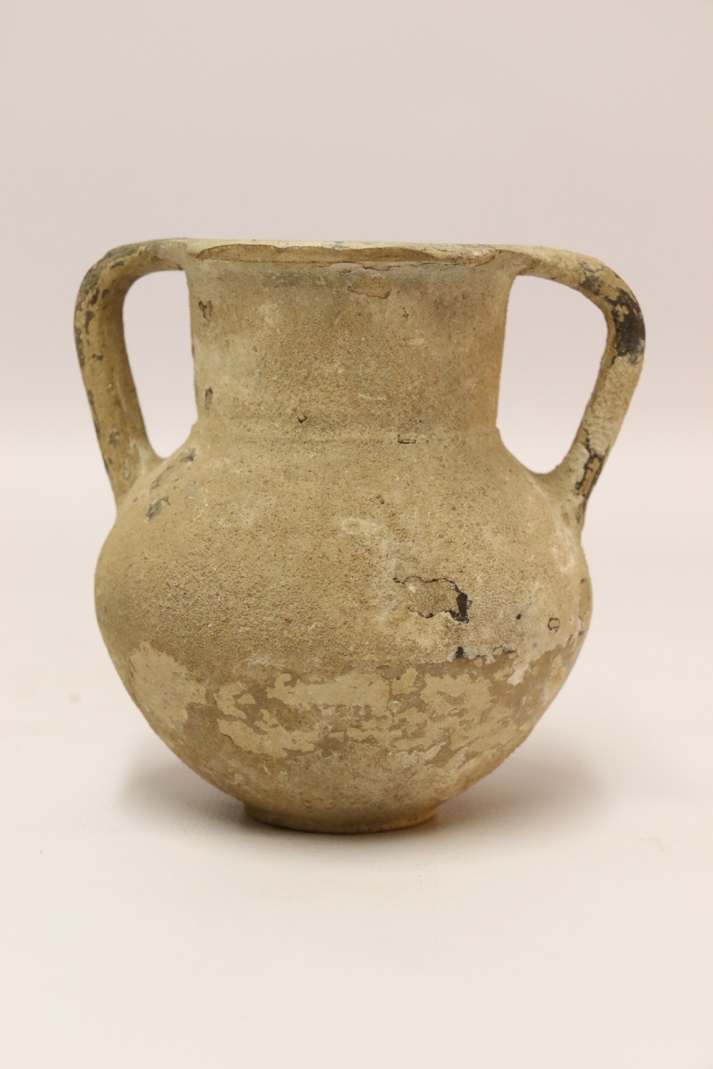 A collection of three unglazed ancient Greek terracotta vessels including a double-handled jar, a small pitcher, and a flattened flask. View II