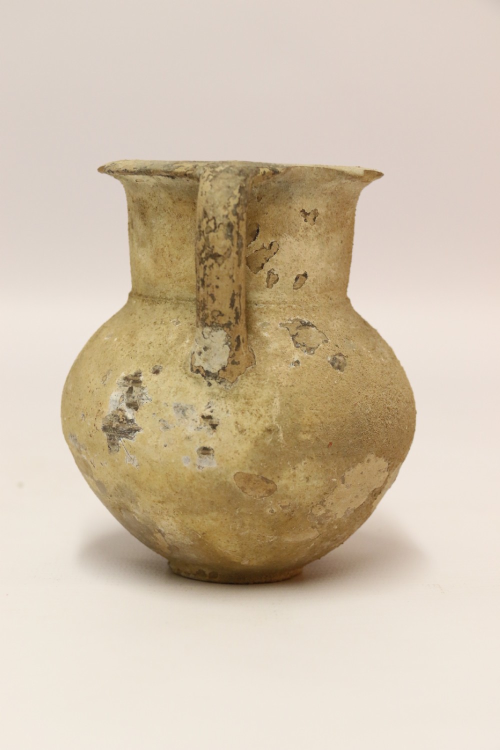 A collection of three unglazed ancient Greek terracotta vessels including a double-handled jar, a small pitcher, and a flattened flask. View III