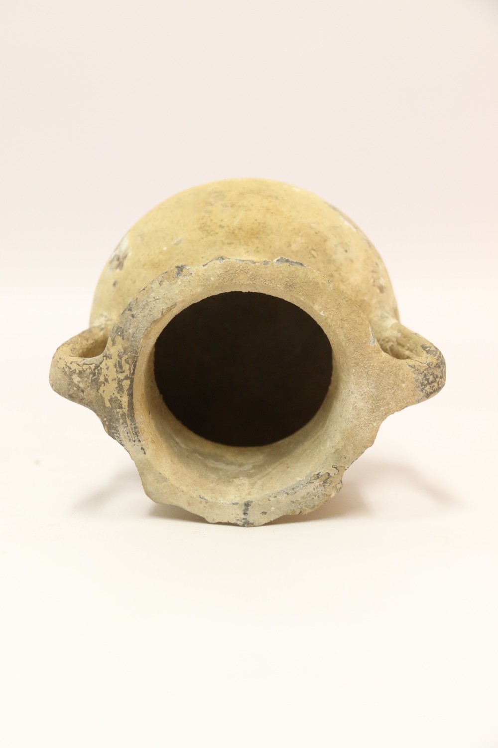 A collection of three unglazed ancient Greek terracotta vessels including a double-handled jar, a small pitcher, and a flattened flask. View V