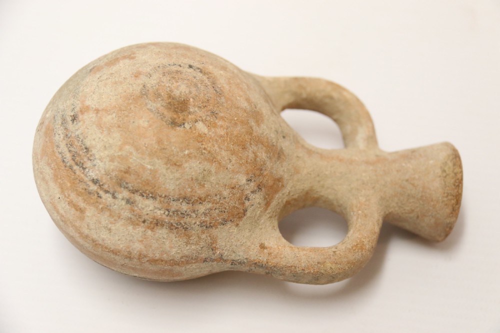 A collection of three unglazed ancient Greek terracotta vessels including a double-handled jar, a small pitcher, and a flattened flask. View VII