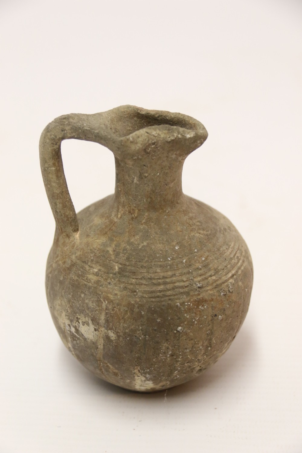 A collection of three unglazed ancient Greek terracotta vessels including a double-handled jar, a small pitcher, and a flattened flask. View XI