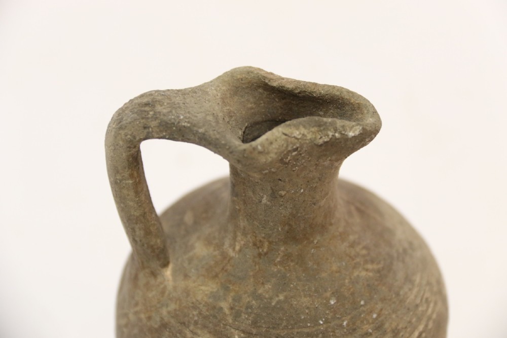A collection of three unglazed ancient Greek terracotta vessels including a double-handled jar, a small pitcher, and a flattened flask. View XII
