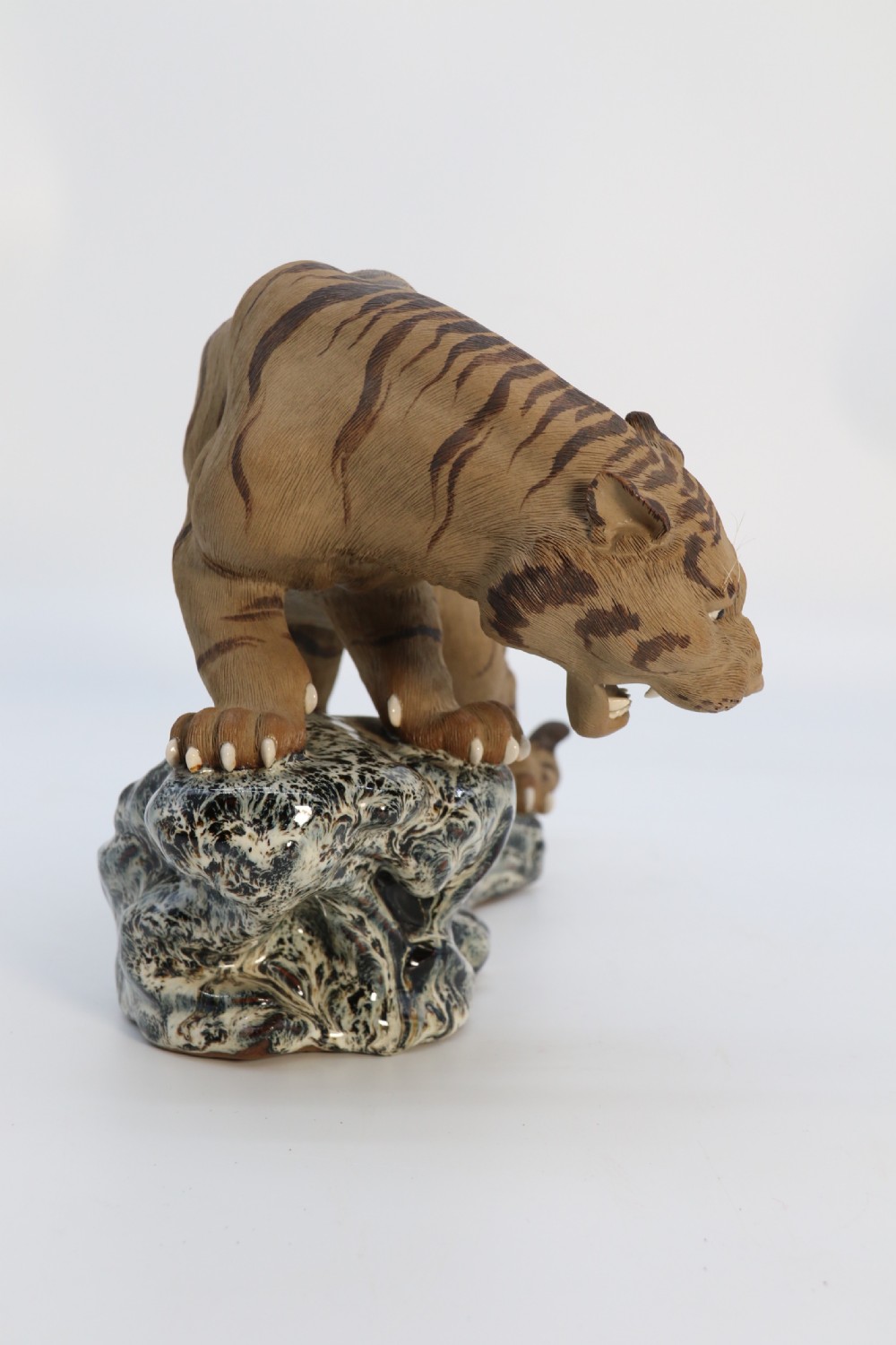 A late 19th-century Chinese Shiwan pottery tiger with incised fur texture and open jaws, standing upon a drip-glazed blue-grey rockwork base. View VI