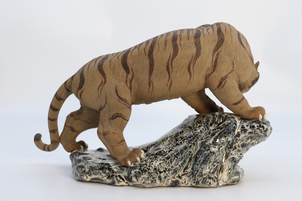 A late 19th-century Chinese Shiwan pottery tiger with incised fur texture and open jaws, standing upon a drip-glazed blue-grey rockwork base. View VIII