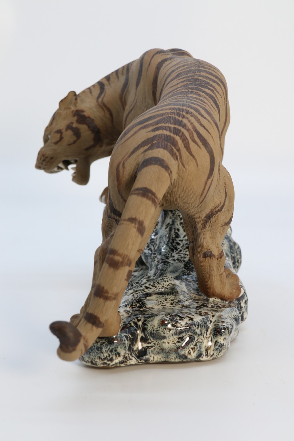 A late 19th-century Chinese Shiwan pottery tiger with incised fur texture and open jaws, standing upon a drip-glazed blue-grey rockwork base. View X