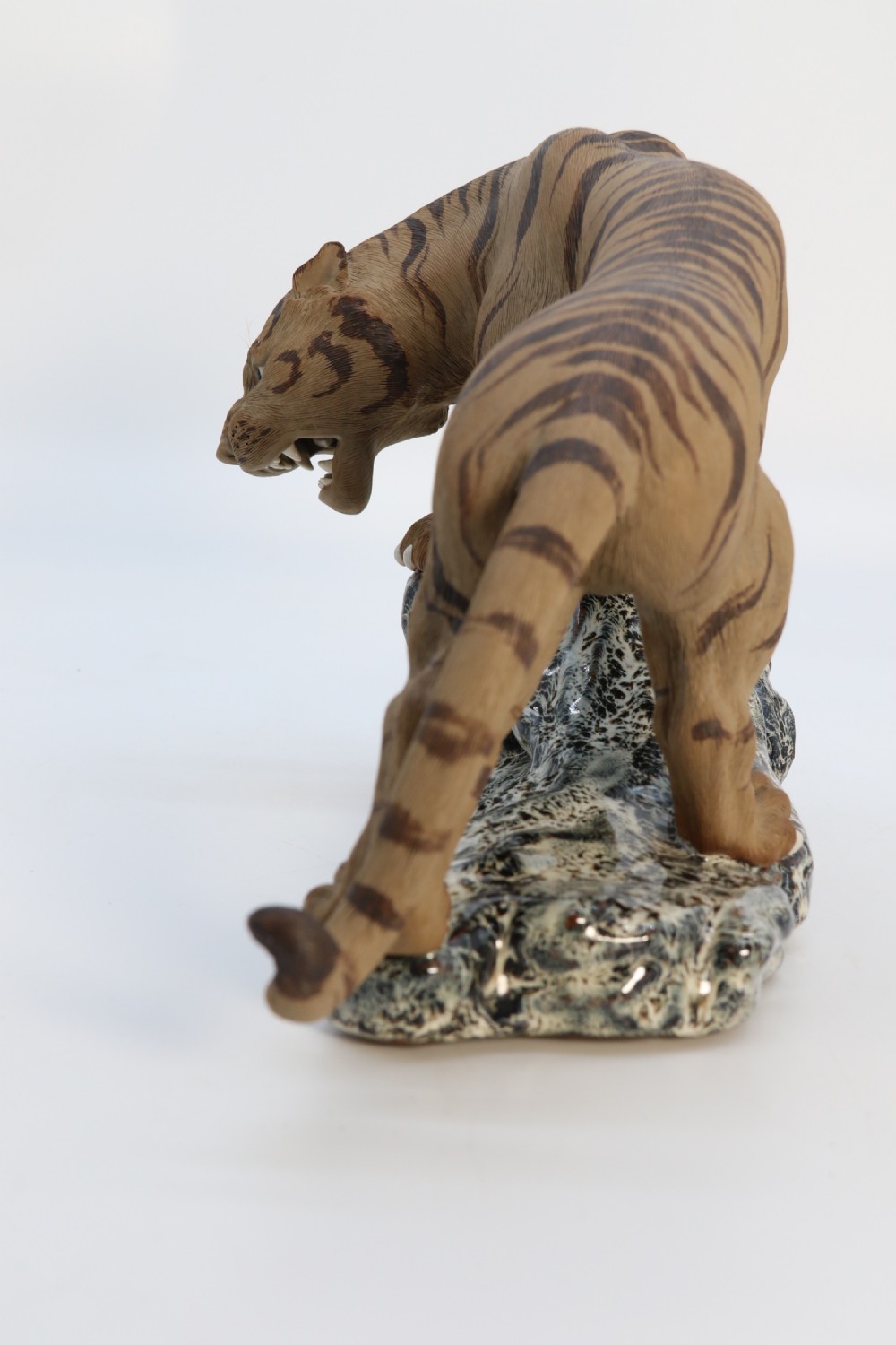 A late 19th-century Chinese Shiwan pottery tiger with incised fur texture and open jaws, standing upon a drip-glazed blue-grey rockwork base. View XI