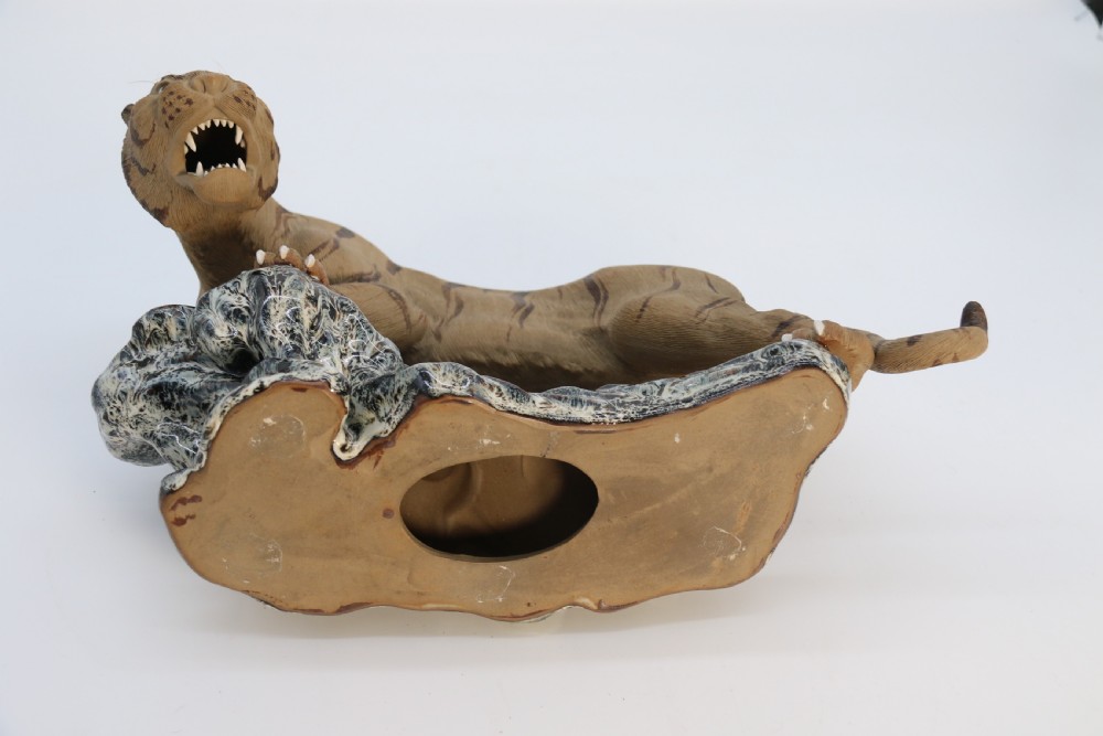 A late 19th-century Chinese Shiwan pottery tiger with incised fur texture and open jaws, standing upon a drip-glazed blue-grey rockwork base. View XVI