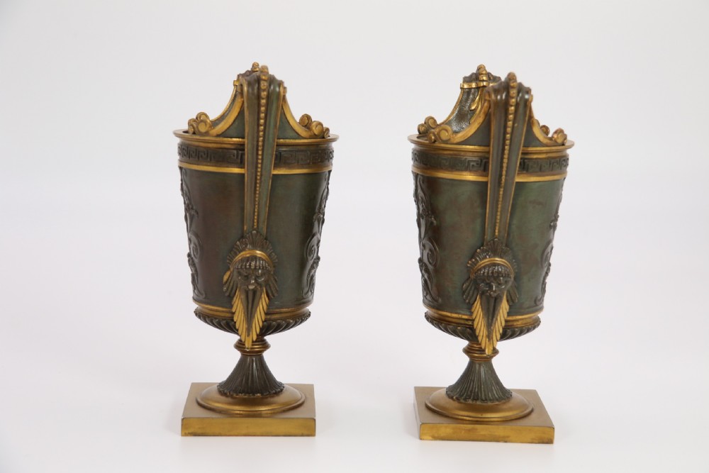 A pair of French Empire patinated and gilt bronze urns with Greek key friezes, scroll handles, and square bases. View II