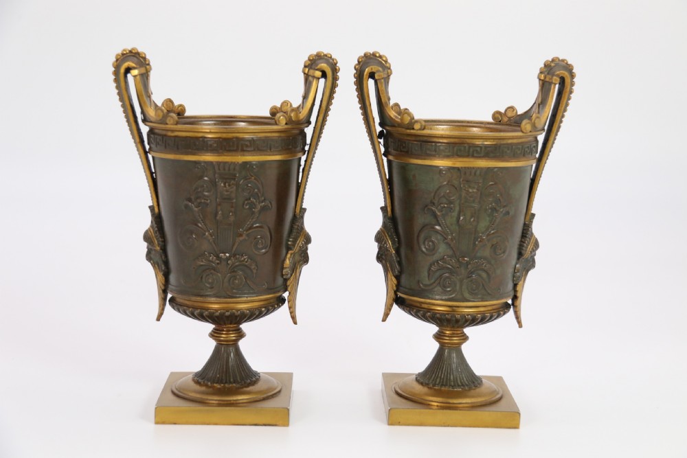 A pair of French Empire patinated and gilt bronze urns with Greek key friezes, scroll handles, and square bases. View IV