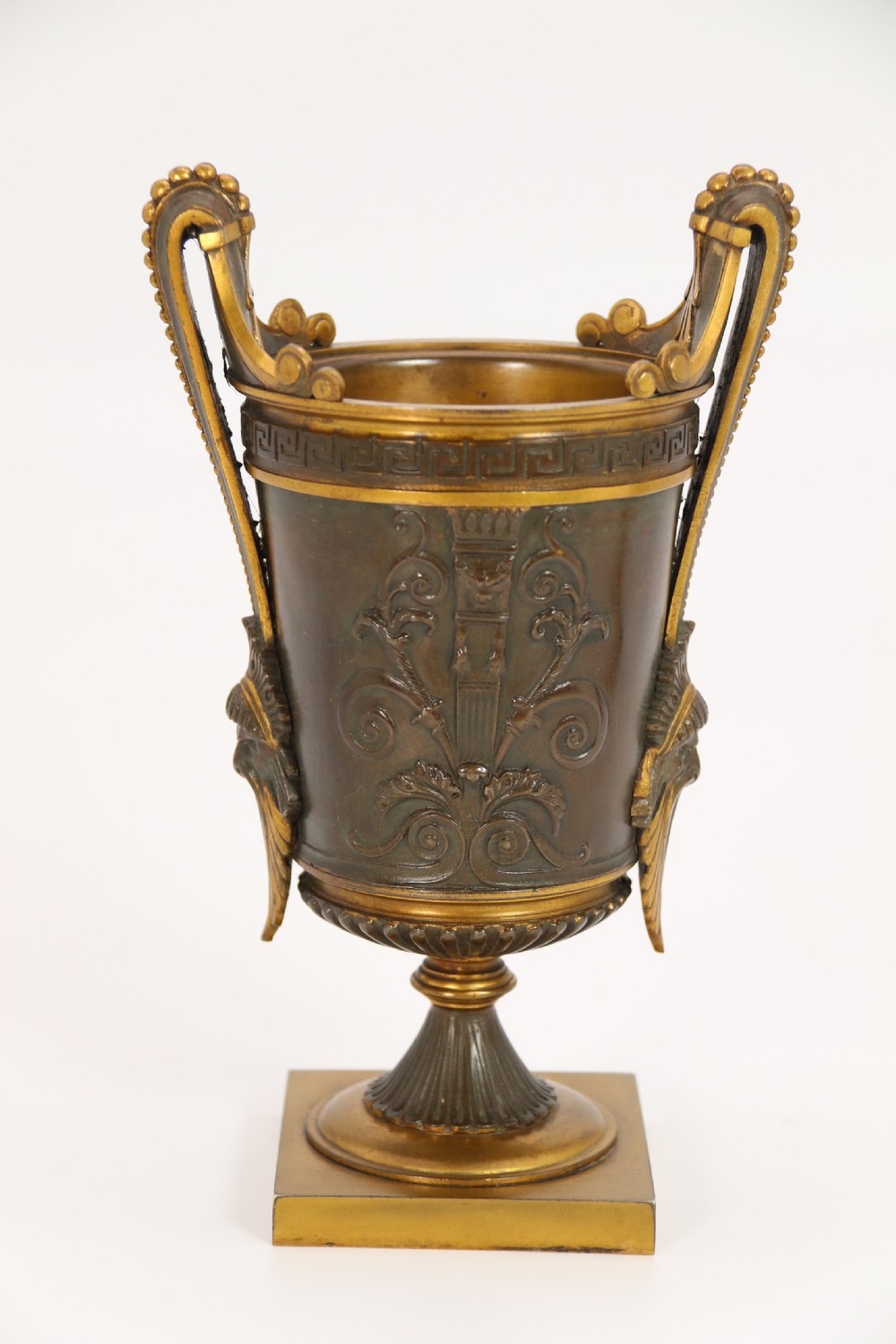 A pair of French Empire patinated and gilt bronze urns with Greek key friezes, scroll handles, and square bases. View V